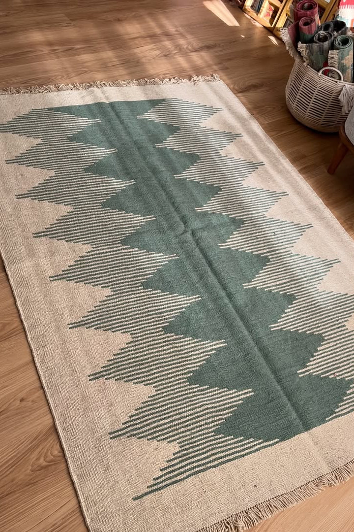 Green and beige patterned rug on a wooden floor