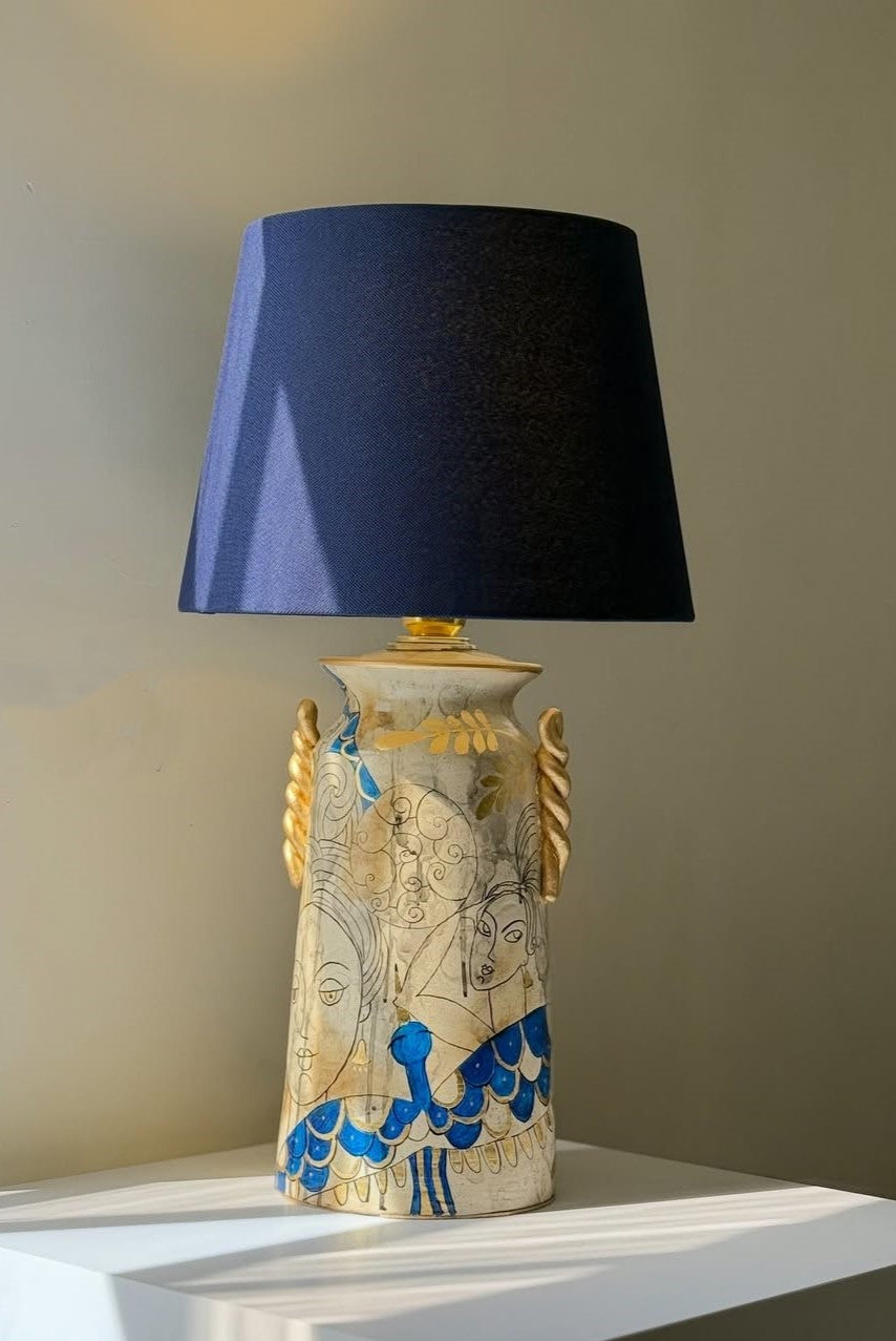 Decorative lamp with a blue shade on a white surface against a beige wall