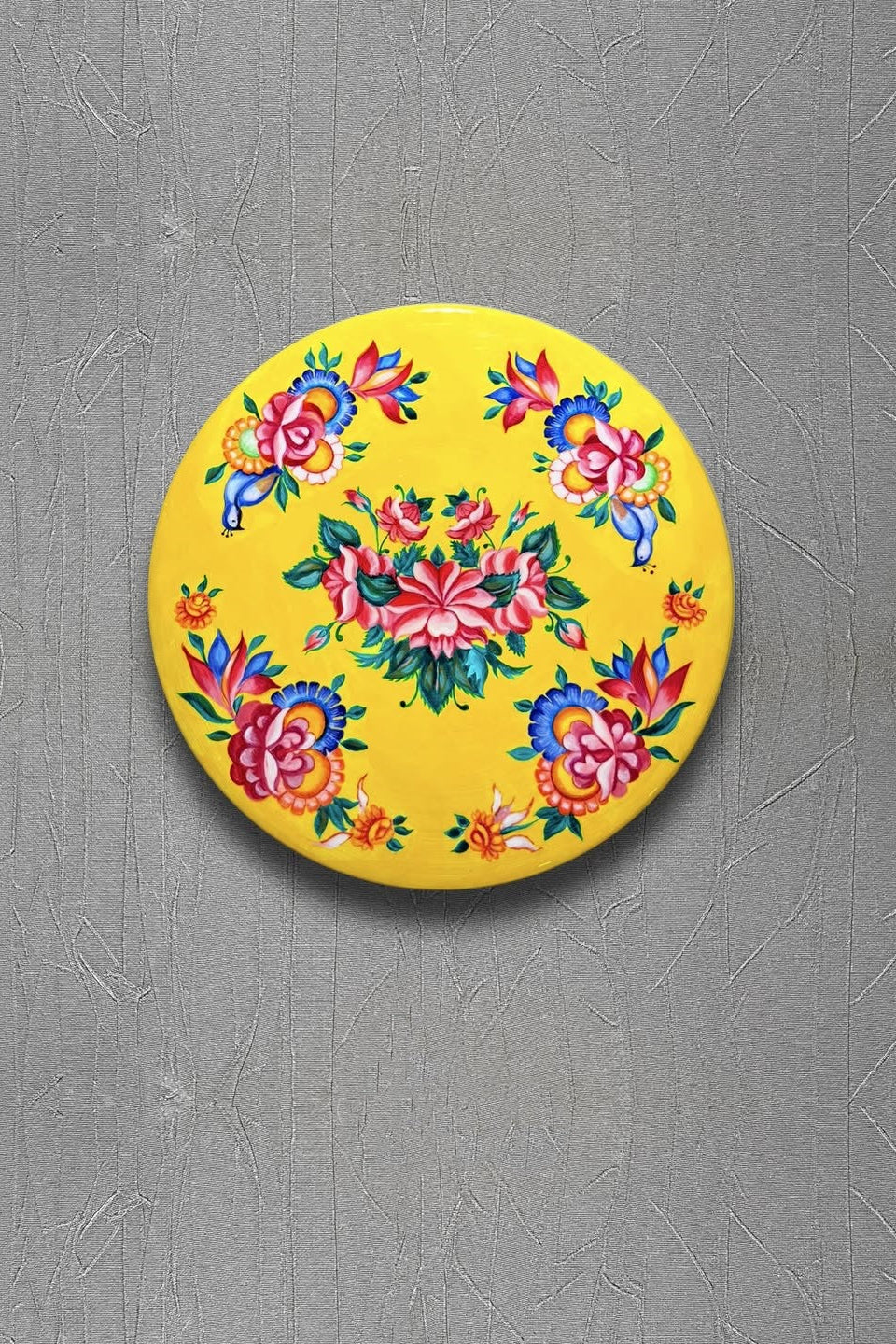 Round yellow coaster with colorful floral design on a gray surface