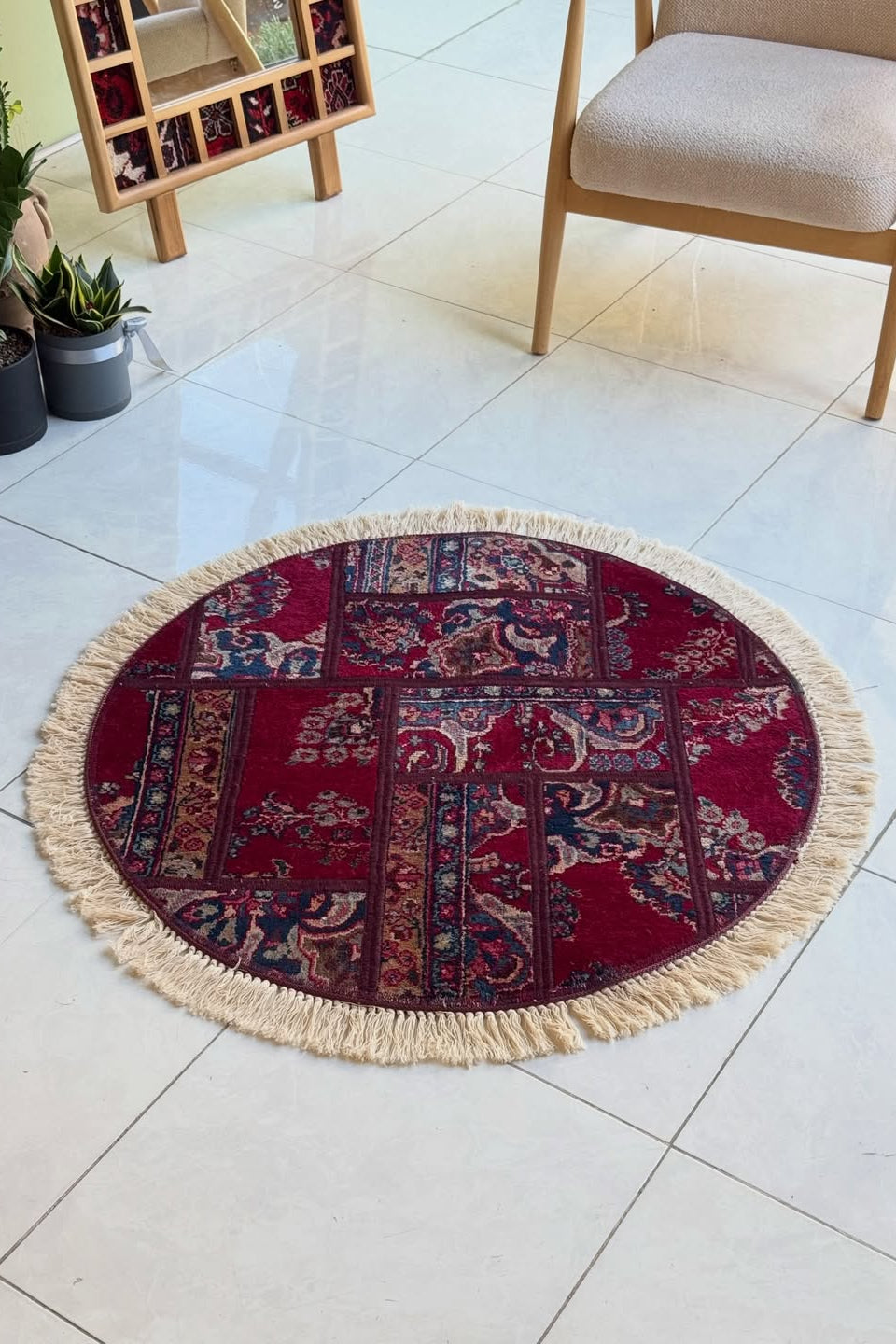 Round patchwork rug with fringes on a tiled floor