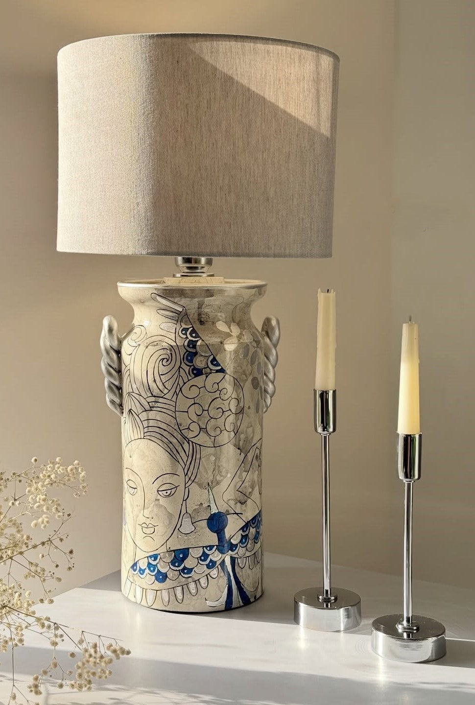 Decorative lamp with a unique design on a white surface, accompanied by two candle holders.