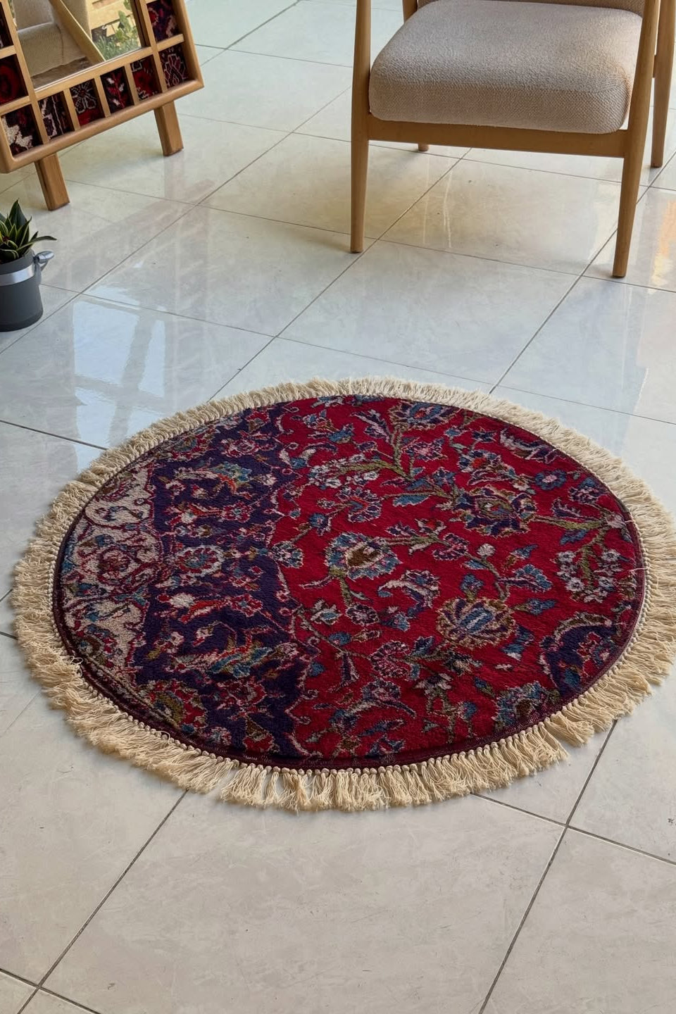 Round decorative rug with fringe on a tiled floor