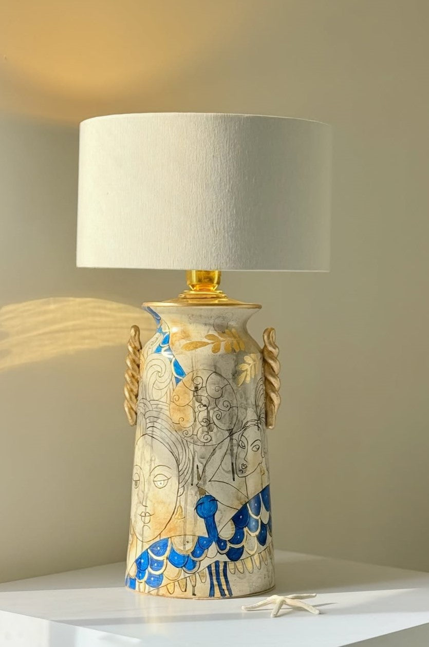 Decorative lamp with a ceramic base featuring artistic designs on a neutral background