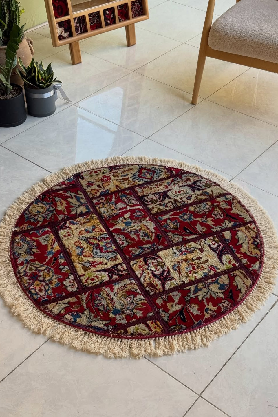 Round patterned rug with tassels on a tiled floor
