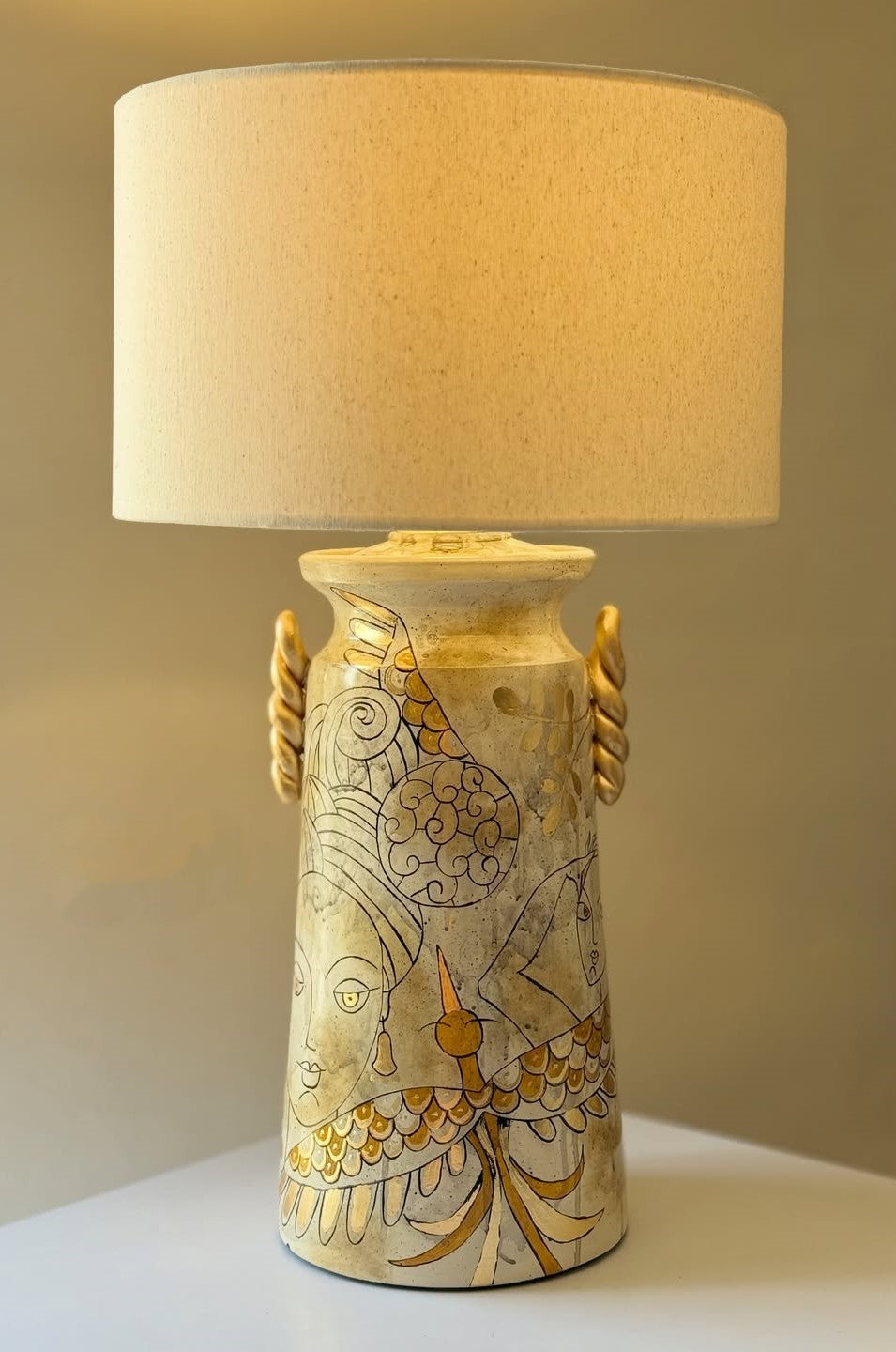 Decorative table lamp with a beige shade and intricate design on the base.