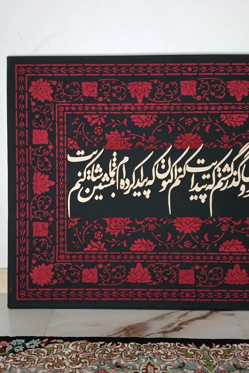 Decorative black and red rug with intricate patterns on a white floor.