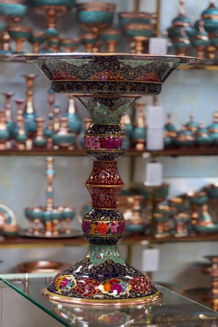 Decorative candle holder with colorful gemstone-like embellishments on a glass surface.