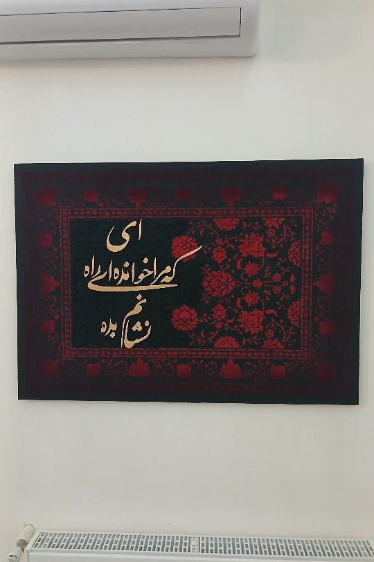 Decorative wall hanging with Arabic text and floral patterns on a white wall.