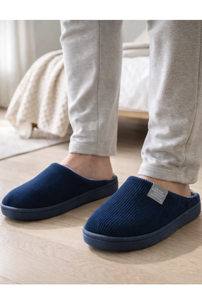 Person wearing navy blue slippers on a wooden floor with a blurred background