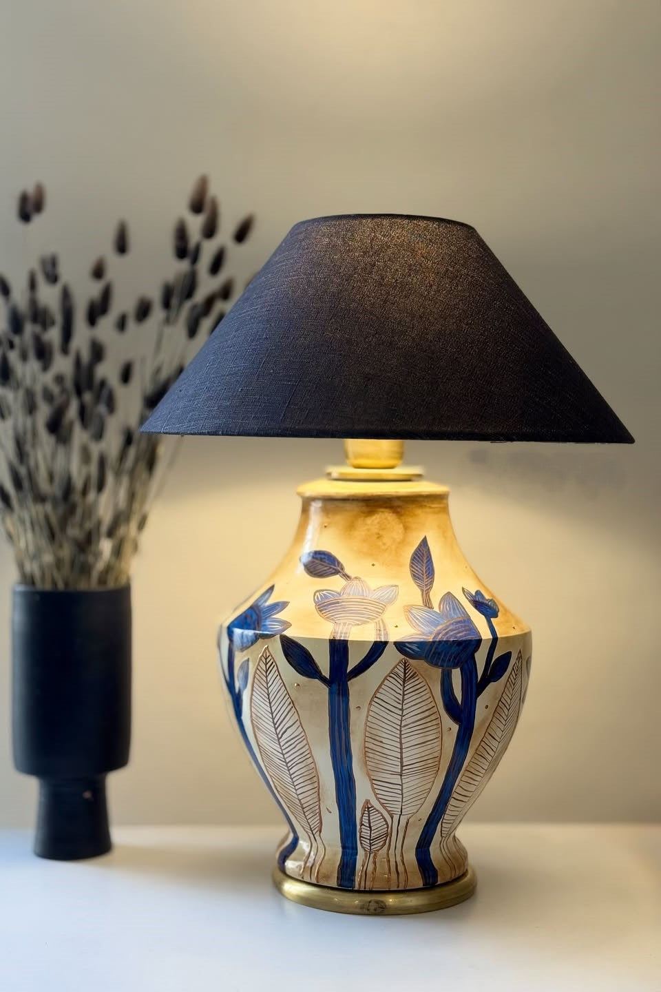 Decorative lamp with black shade and floral design on a white surface
