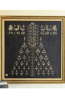 Decorative wall art with geometric pattern in a gold frame on a light-colored wall.