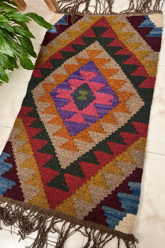Colorful geometric-patterned rug with fringes on a light-colored floor.